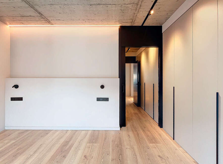 Modern minimalist apartment boasts sleek design, featuring light oak flooring, recessed lighting, and built-in wardrobes.