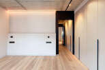 Modern minimalist apartment boasts sleek design, featuring light oak flooring, recessed lighting, and built-in wardrobes.