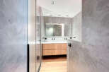 Modern bathroom with double vanity and walk-in shower, featuring sleek light wood cabinets and a minimalist design.