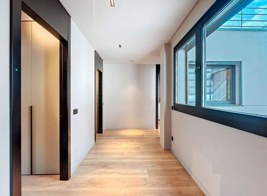 This stunning hallway boasts sleek, modern design with dark-framed doors and windows offering ample natural light.