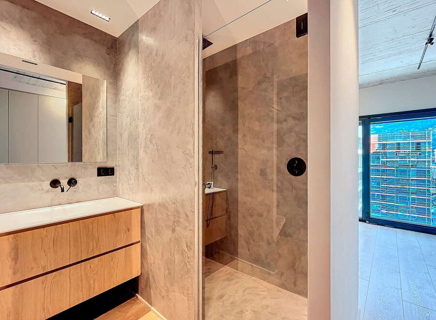 Modern bathroom with a walk-in shower, sleek wooden vanity, and large mirror reflecting a bright, open space.