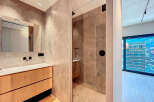Modern bathroom with a walk-in shower, sleek wooden vanity, and large mirror reflecting a bright, open space.