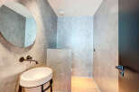 Modern bathroom with concrete walls, a round mirror, and a sleek sink.