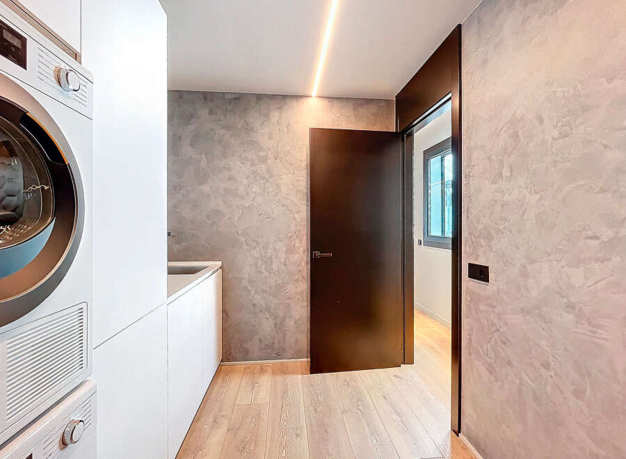 Modern laundry room with built-in white cabinets and high-end appliances.