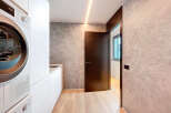 Modern laundry room with built-in white cabinets and high-end appliances.