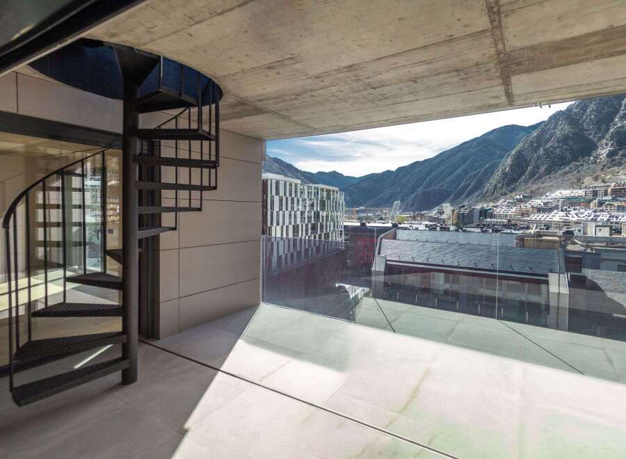 Modern apartment with stunning mountain views and a sleek spiral staircase.