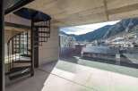 Modern apartment with stunning mountain views and a sleek spiral staircase.