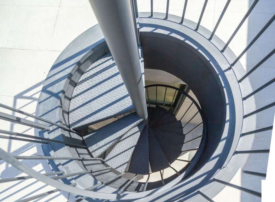 Modern spiral staircase with metal railings and diamond plate treads.