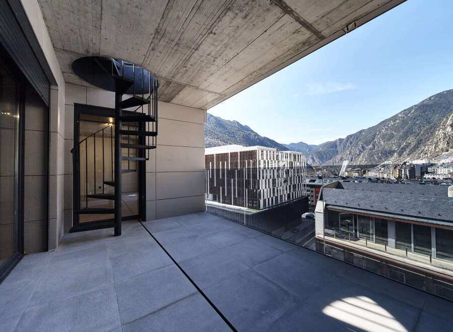 This stunning penthouse boasts a spacious balcony with breathtaking mountain views and a modern spiral staircase.