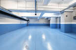 This spacious parking garage boasts a modern design with bright blue epoxy flooring and clean white and gray walls.
