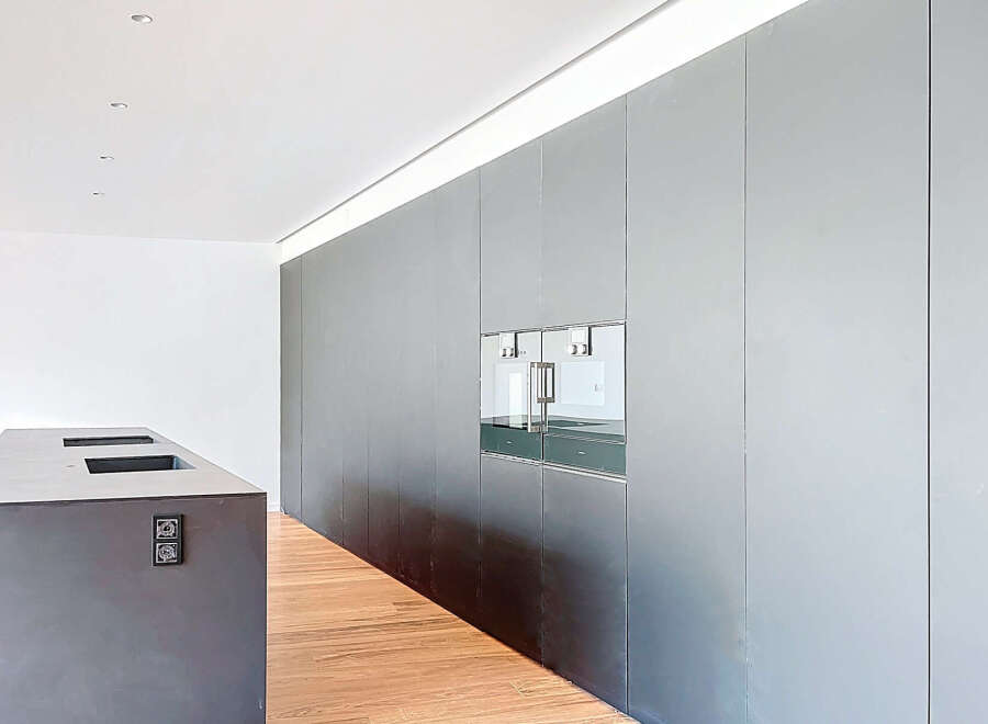 Modern kitchen with sleek, dark gray cabinetry and integrated appliances.