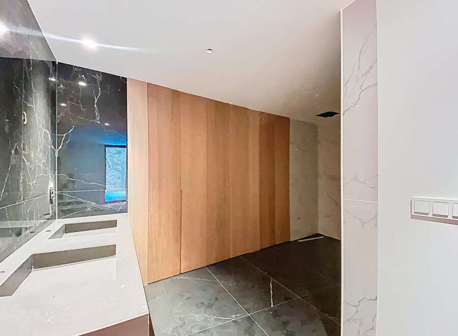 Luxurious bathroom boasts double sinks with marble countertops and dark marble wall tiles.