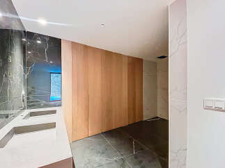 Luxurious bathroom boasts double sinks with marble countertops and dark marble wall tiles.