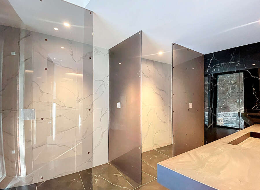 Luxury bathroom boasts stunning marble tile and sleek glass partitions, creating a spa-like atmosphere.