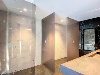 Luxury bathroom boasts stunning marble tile and sleek glass partitions, creating a spa-like atmosphere.