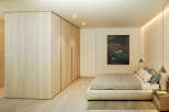 This stunning bedroom boasts a minimalist design with built-in light wood wardrobes and a plush platform bed.
