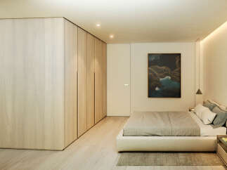 This stunning bedroom boasts a minimalist design with built-in light wood wardrobes and a plush platform bed.
