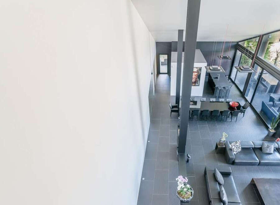 This stunning modern home boasts an open floor plan with sleek, dark gray tile floors and floor-to-ceiling windows offering breathtaking views.