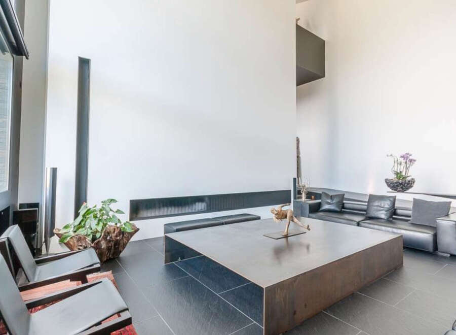 Modern living space featuring sleek black leather seating, a large metal coffee table, and floor-to-ceiling windows.