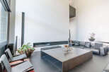 Modern living space featuring sleek black leather seating, a large metal coffee table, and floor-to-ceiling windows.