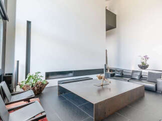 Modern living space featuring sleek black leather seating, a large metal coffee table, and floor-to-ceiling windows.