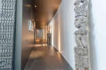 This stunning property boasts a long hallway with dark gray tile flooring, complemented by unique artwork and sculptures.