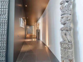 This stunning property boasts a long hallway with dark gray tile flooring, complemented by unique artwork and sculptures.