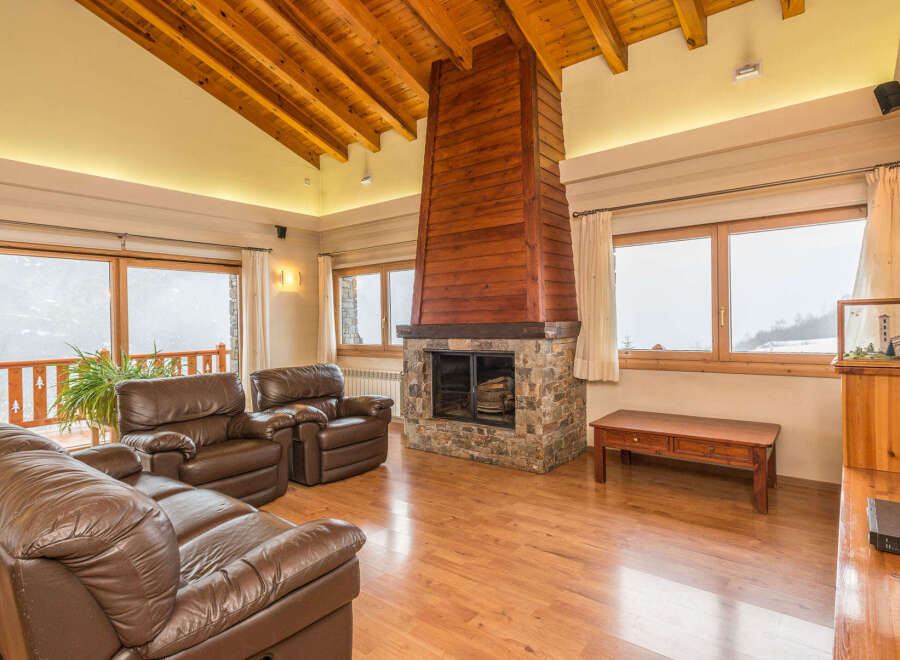 This stunning chalet boasts a spacious living area with floor-to-ceiling windows offering breathtaking mountain views.
