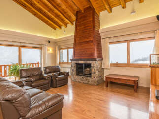 This stunning chalet boasts a spacious living area with floor-to-ceiling windows offering breathtaking mountain views.
