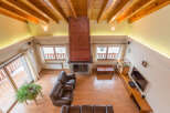This stunning chalet boasts a spacious open-plan living area with high wooden beamed ceilings and a cozy fireplace as the centerpiece.
