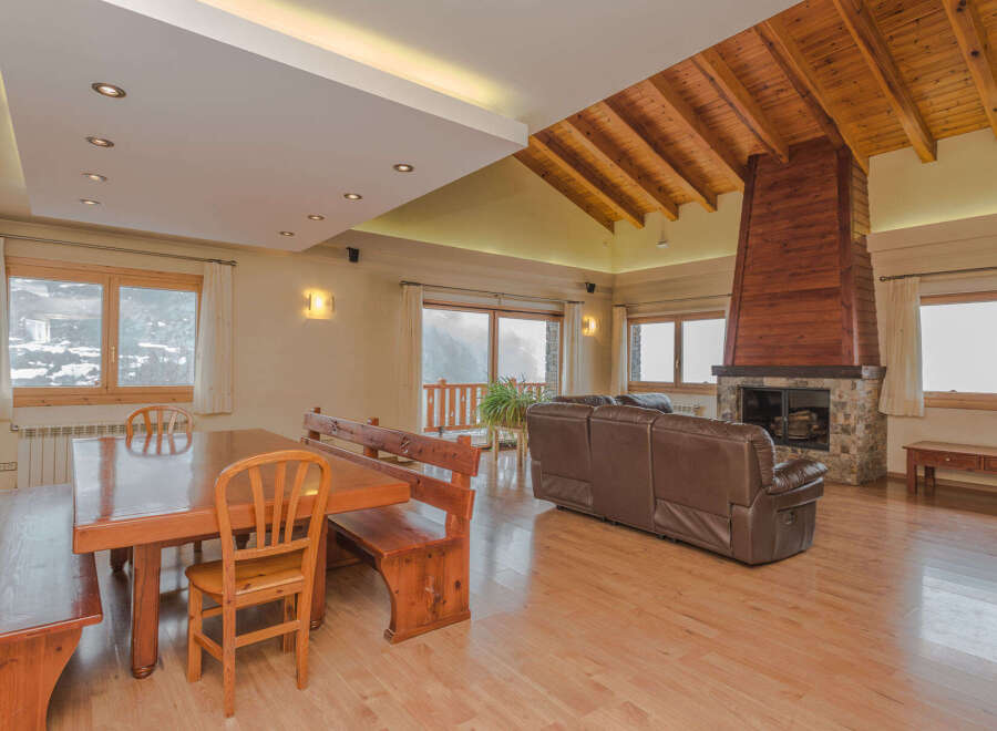 This stunning chalet boasts a spacious open-plan living area with a magnificent wooden beamed ceiling and a cozy fireplace, perfect for relaxing after a day on the slopes.