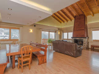 This stunning chalet boasts a spacious open-plan living area with a magnificent wooden beamed ceiling and a cozy fireplace, perfect for relaxing after a day on the slopes.