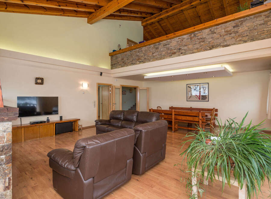 This stunning property boasts a spacious open-plan living area with high ceilings and exposed wooden beams, creating a warm and inviting atmosphere.