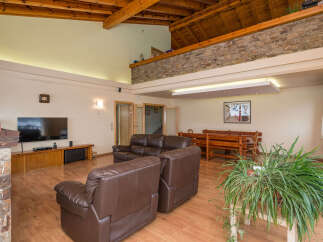This stunning property boasts a spacious open-plan living area with high ceilings and exposed wooden beams, creating a warm and inviting atmosphere.