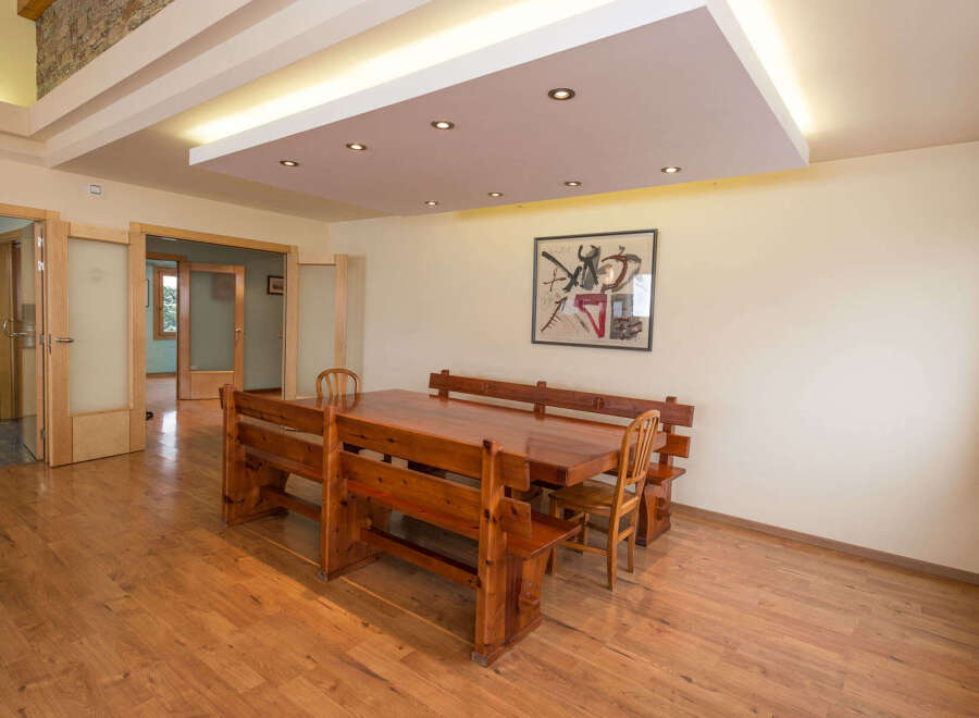 This stunning property boasts a spacious dining area with a large wooden table and built-in benches, perfect for family gatherings.
