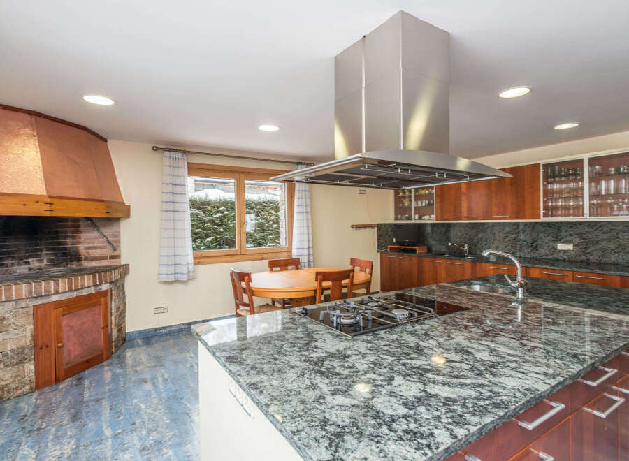 This stunning kitchen boasts a large granite island with built-in gas cooktop, providing ample space for cooking and entertaining.