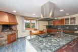 This stunning kitchen boasts a large granite island with built-in gas cooktop, providing ample space for cooking and entertaining.