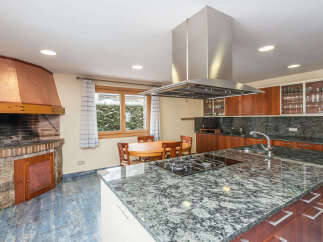 This stunning kitchen boasts a large granite island with built-in gas cooktop, providing ample space for cooking and entertaining.