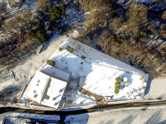 Nestled in a snow-covered landscape, this property boasts a spacious building with a unique architectural design.