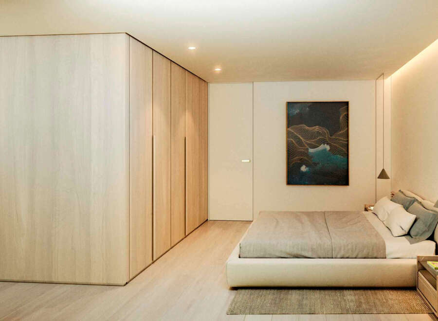 This stunning bedroom boasts a minimalist design with built-in light wood wardrobes and a plush platform bed.