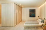 This stunning bedroom boasts a minimalist design with built-in light wood wardrobes and a plush platform bed.