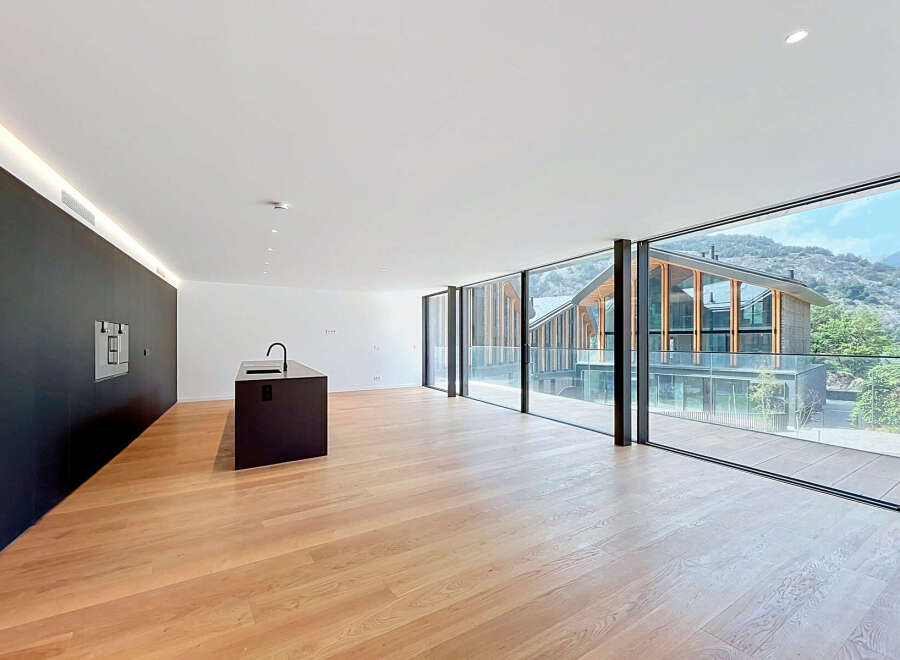Experience modern living in this spacious open-plan apartment, featuring a sleek black kitchen island with a built-in sink and a minimalist black wall with integrated appliances.