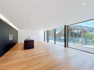 Experience modern living in this spacious open-plan apartment, featuring a sleek black kitchen island with a built-in sink and a minimalist black wall with integrated appliances.