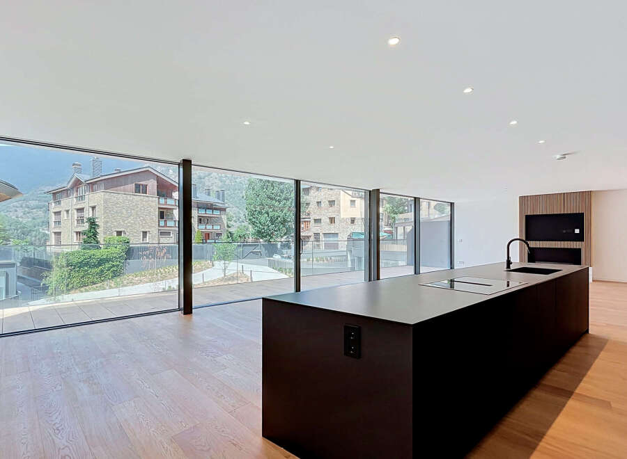Experience modern living in this stunning open-plan kitchen and living area, featuring expansive floor-to-ceiling windows that offer breathtaking mountain views.