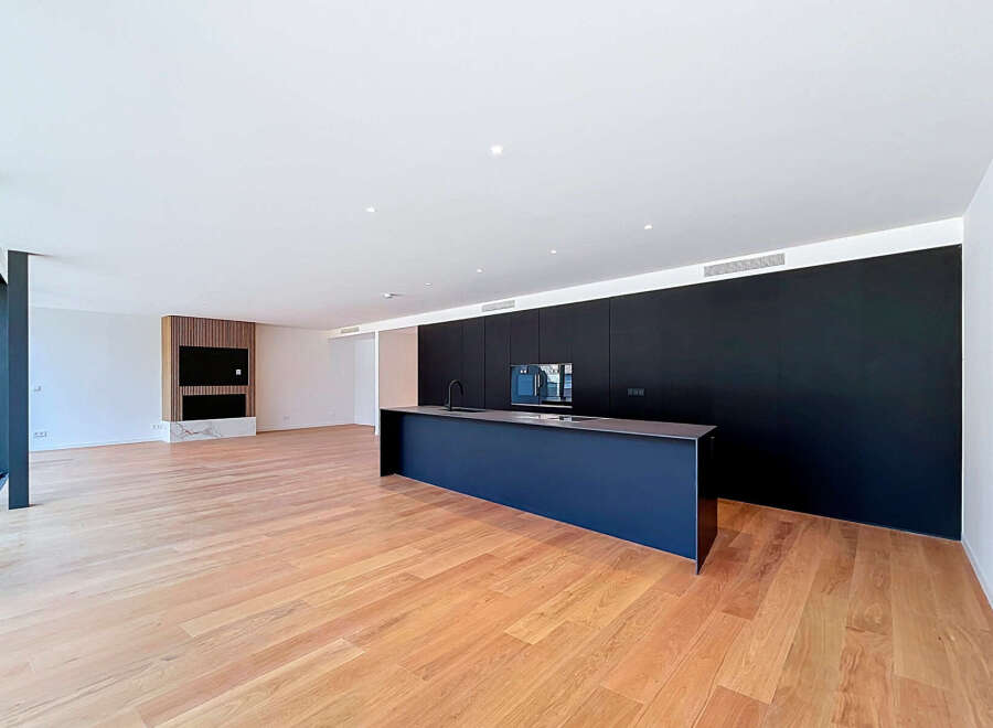 Experience modern living in this spacious open-plan apartment featuring a sleek, dark kitchen island and integrated cabinetry.