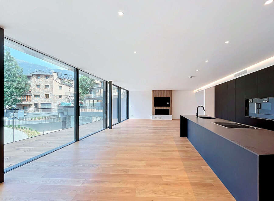 Experience modern luxury in this spacious open-concept living area featuring a sleek, minimalist kitchen with dark cabinetry and a large island.