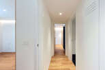 Step into this modern hallway featuring sleek white walls and a warm, inviting wooden floor.