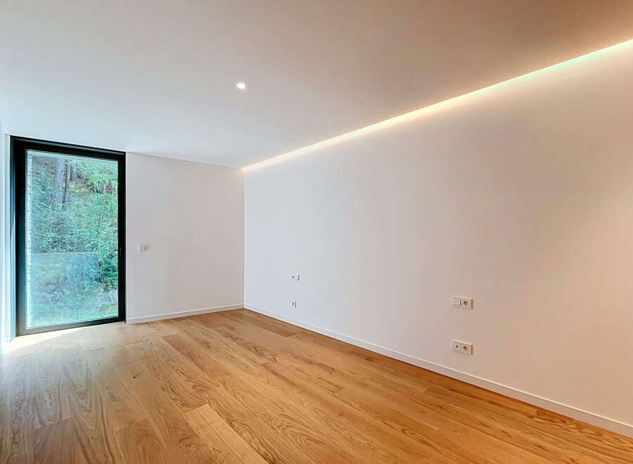 Experience modern living in this bright and airy room featuring a large floor-to-ceiling window that floods the space with natural light.