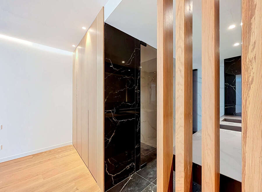Experience modern luxury with this stunning interior featuring sleek, light wood cabinetry that seamlessly integrates with a dramatic black marble accent wall.