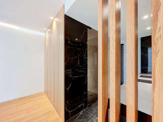 Experience modern luxury with this stunning interior featuring sleek, light wood cabinetry that seamlessly integrates with a dramatic black marble accent wall.